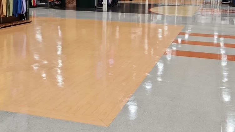 Mixed flooring at Dick's Sporting Goods — VCT, wood-look LVT, and polished concrete