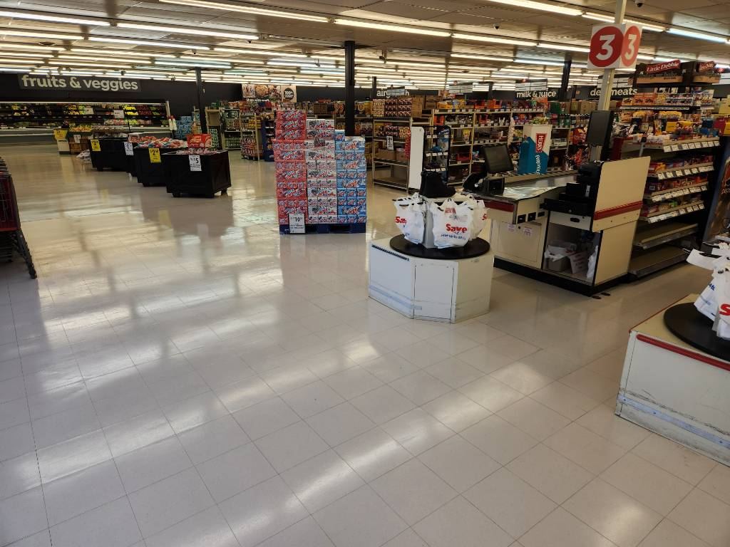 Save A Lot entrance and checkout area with restored VCT floor finish reflecting natural light