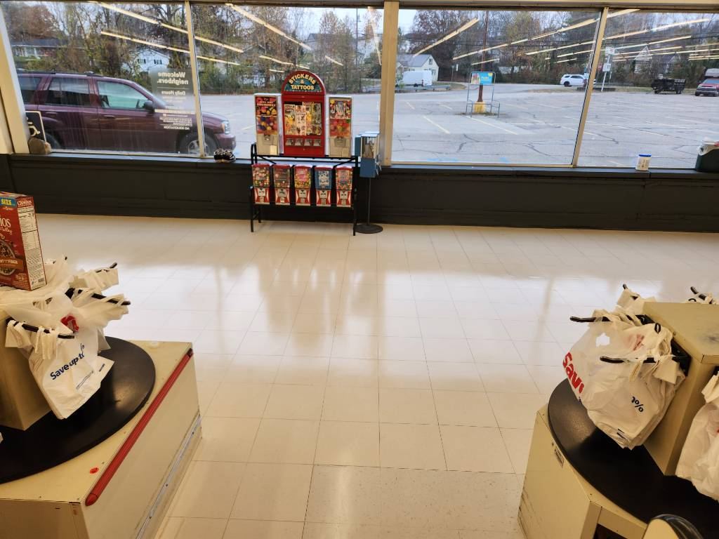 Save A Lot retail salesfloor after VCT recovery — wide view across fruits, deli, and milk sections with clean reflective finish